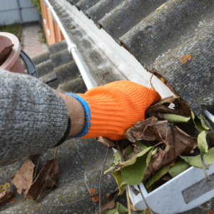 roofer doing gutter cleaning for roof maintenance